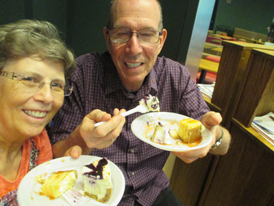 Photo shows a selfie of Dona and Gene each with a plate of cheesecake.
